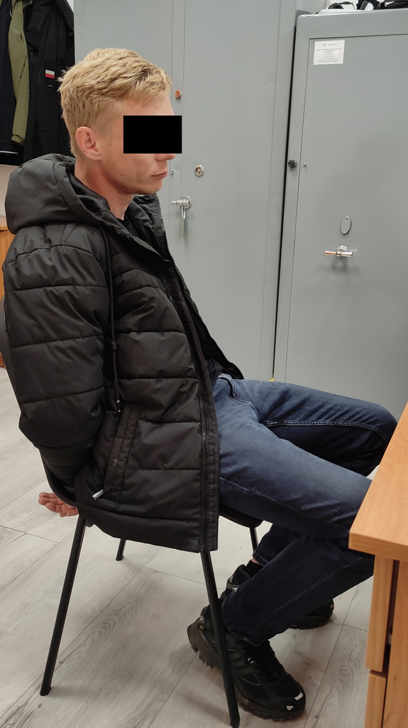 zatrzymany skuty kajdankami siedzi na krześle