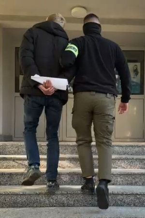 policjant prowadzi zatrzymanego