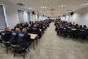 policjanci siedzą w ławkach na sali