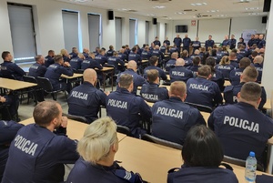 policjanci siedzą w ławkach na sali