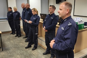 policjantka odczytuje z kartki, obok stoją inni policjanci