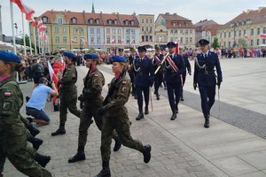 Zaproszone służby mundurowe stoją na placu starego rynku podczas obchodów Dnia Flagi Rzeczypospolitej Polskiej
