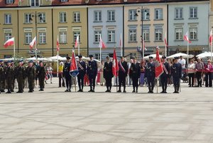 Zaproszone służby mundurowe stoją na placu starego rynku podczas obchodów Dnia Flagi Rzeczypospolitej Polskiej