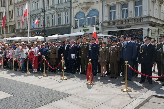 Zaproszone służby mundurowe stoją na placu starego rynku podczas obchodów Dnia Flagi Rzeczypospolitej Polskiej