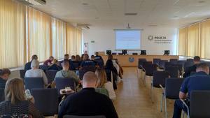 Sala szkoleniowa, słuchacze, umundurowani policjanci i osoby w cywilnym ubiorze.