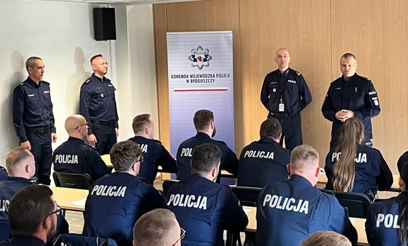 Komendant przemawia do policjantów siedzących w ławkach