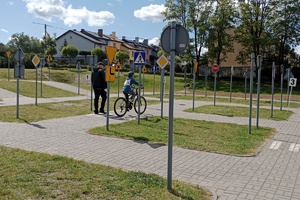 dzieci biorą udział w Wojewódzkim Turnieju Bezpieczeństwa w Ruchu Drogowym dla uczniów Szkół Specjalnych, piszą test i jeżdżą rowerem obok policjanta