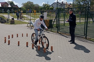 dzieci biorą udział w Wojewódzkim Turnieju Bezpieczeństwa w Ruchu Drogowym dla uczniów Szkół Specjalnych, piszą test i jeżdżą rowerem obok policjanta