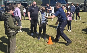Policjanci wzięli udział w pikniku profilaktycznym w Osiu, pokazują uczestnikom policyjny sprzęt i biorą udział w zabawach z najmłodszymi
