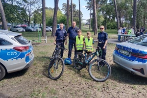 policjanci z dwójką dzieci ubranych w kamizelki odblaskowe pozują do zdjęcia