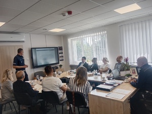 Osoby siedzące przy stole w trakcie spotkania.