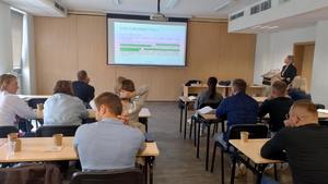 nieumundurowani policjanci siedzą w ławkach i patrzą na wyświetlane prezentacje