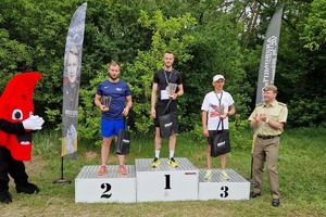 zawodnicy stoją na podium i trzymają puchary