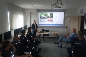 policjanci siedzą na krzesłach w sali i słuchają wykładu biegłego