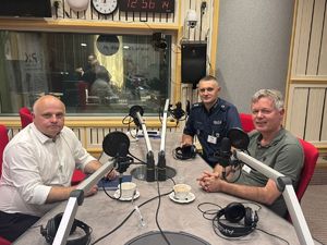 policjant z gośćmi siedzi w studiu radiowym
