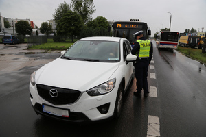 Policjant RD kontroluje trzeźwość kierowcy białej mazdy