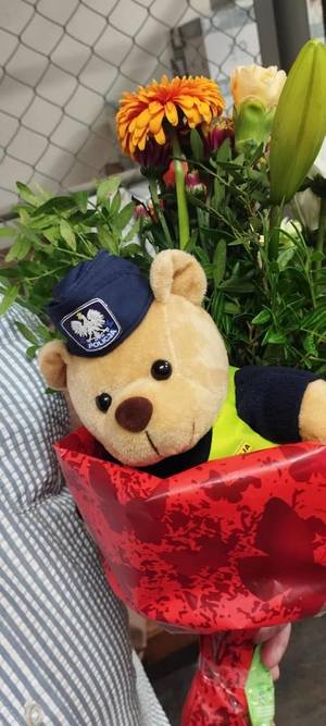 Zdjęcie bukietu z maskotką z czapką policyjną. Plik Jpg.