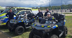 Trzej funkcjonariusze stoją przy oznakowanych pojazdach a na dwóch siedzą dzieciaki