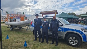 Zastępca Komendanta Wojewódzkiego i dwóch innych policjantów stoją na tle radiowozu i policyjnej łodzi