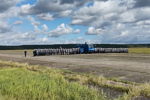 policjanci ćwiczą na płycie lotniska. Funkcjonariusze ustawieni są w szeregu. Pomiędzy nimi jedzie policyjny pojazd z wodą