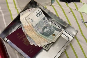 plik banknotów 100 zł i paszport leżą na tacy