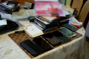 policjanci przeszukują pomieszczenia w domu podejrzanego i na komputerze sprawdzają zawartość nośników cyfrowych