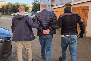 policjanci prowadzą mężczyznę skutego kajdankami