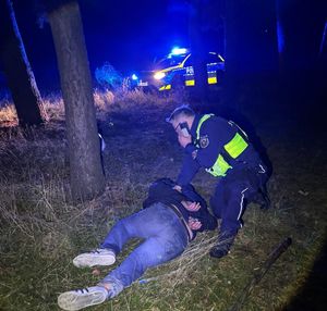 Policjant przytrzymuje leżącego na ziemi motocyklistę