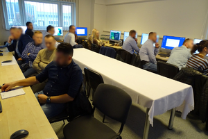 nieumundurowani policjanci siedzą przed komputerami i słuchają prowadzącego szkolenie