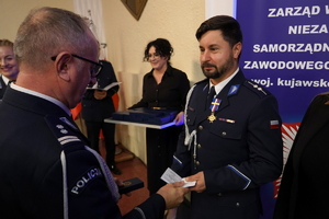 policjanci i pracownicy cywilni biorą udział z okazji rocznicy związków zawodowych, które odbywają się w wojskowym kinoteatrze. Przedstawiciele związków odznaczają wyróżnionych