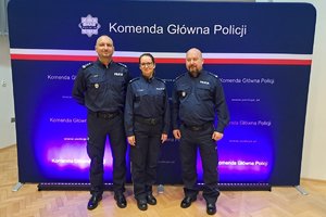 troje policjantów pozuje do zdjęcia na tle baneru KGP