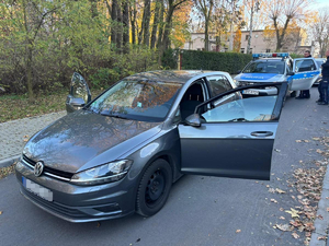 policjanci stoją koło zabezpieczonego pojazdu