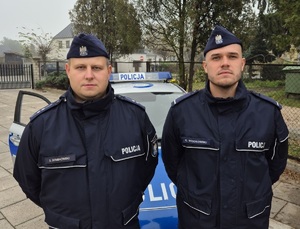 Patrol policjantów przy radiowozie.