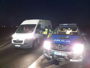 Stoi radiowóz obok dostawczak i policjant kontroluje trzeźwość kierowcy