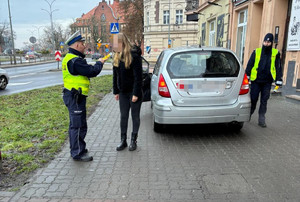 Policjant kontroluje trzeźwość kierującej, a obok stoi policjantka, która się przygląda