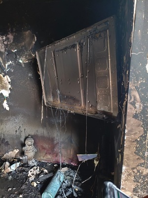 Policjanci przy radiowozie oraz miejsce pożaru domu.