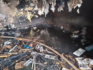 Policjanci przy radiowozie oraz miejsce pożaru domu.