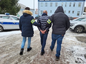 policjanci prowadzą zatrzymanego skutego kajdankami