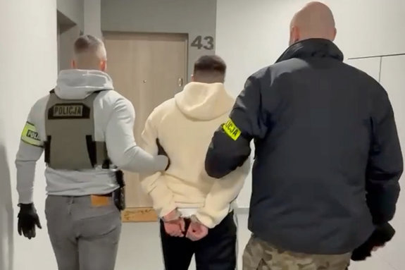 nieumundurowani policjanci prowadzą zatrzymanego