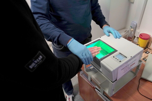 mężczyzna przykłada palce do skanującego urządzenia