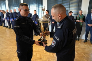 policjant wręcza Komendantowi zdobyty puchar