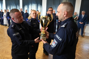 policjant wręcza Komendantowi zdobyty puchar