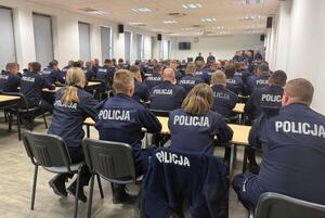 policjanci siedzą w ławkach i słuchają wypowiedzi stojącego przed nimi Komendanta