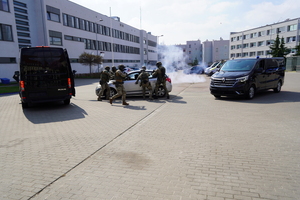 policyjni kontrterroryści stoją przy samochodach i zatrzymują osobę