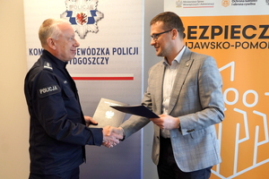 Wojewoda i Komendant podają sobie rękę i wymieniają dokumenty