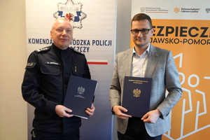 Wojewoda i Komendant pozują z dokumentami do zdjęcia