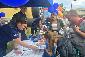 Policjanci na pikniku profilaktycznym, prezentują sprzęt oraz prowadzą gry i zabawy dla dzieci