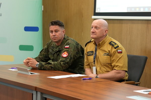 żołnierz i strażak siedzą w sali na krzesłach