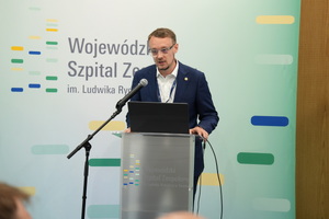 prelegent prowadzi szkolenie i mówi do zaproszonych gości siedzących w sali na krzesłach