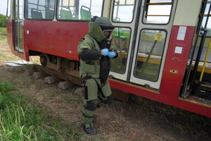 policyjny pirotechnik ubiera specjalistyczny kombinezon i udaje się do tramwajów, gdzie sprawdza podejrzane pakunki